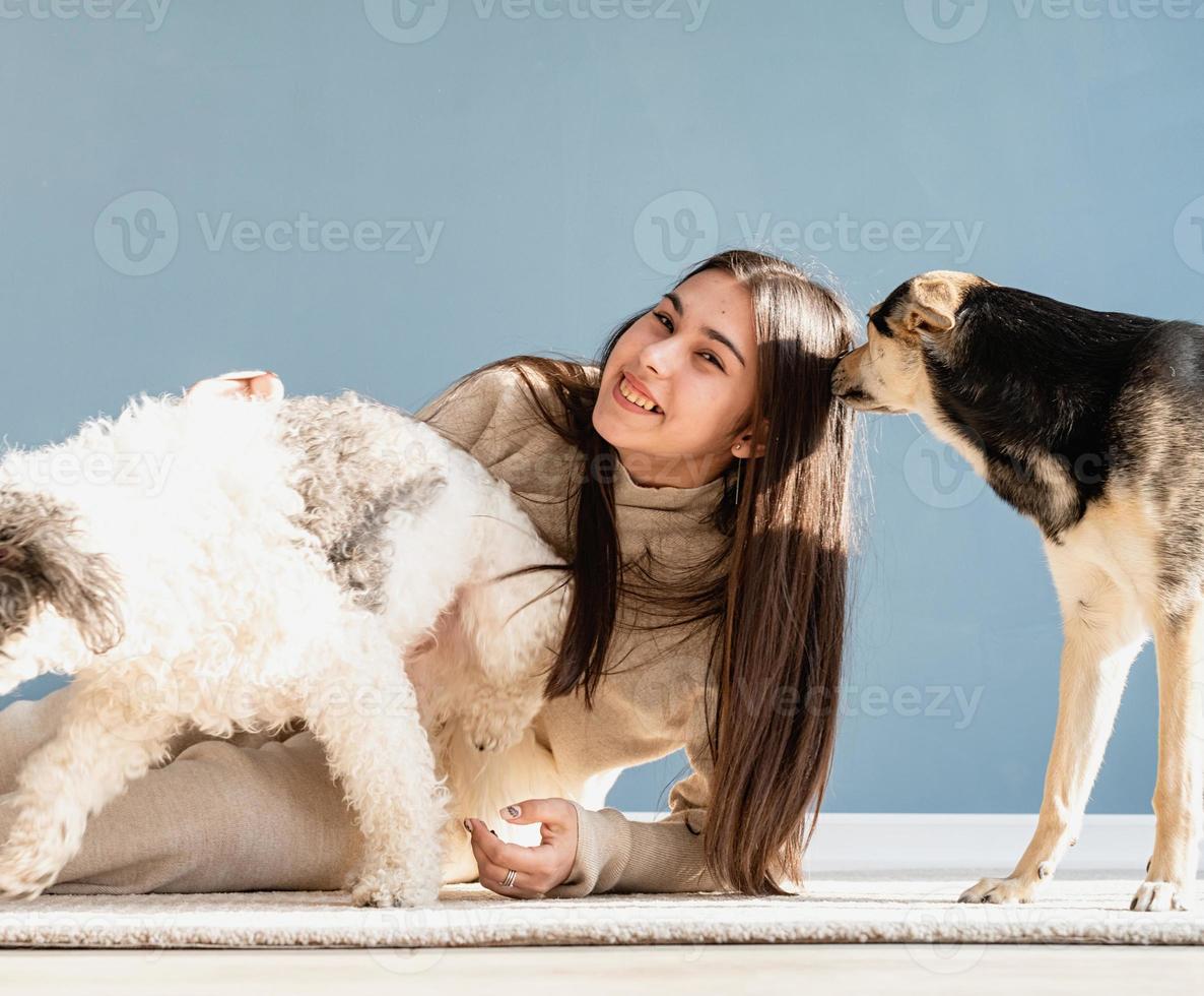 schöne Frau mit verspielten Hunden, die sich zu Hause umarmen foto