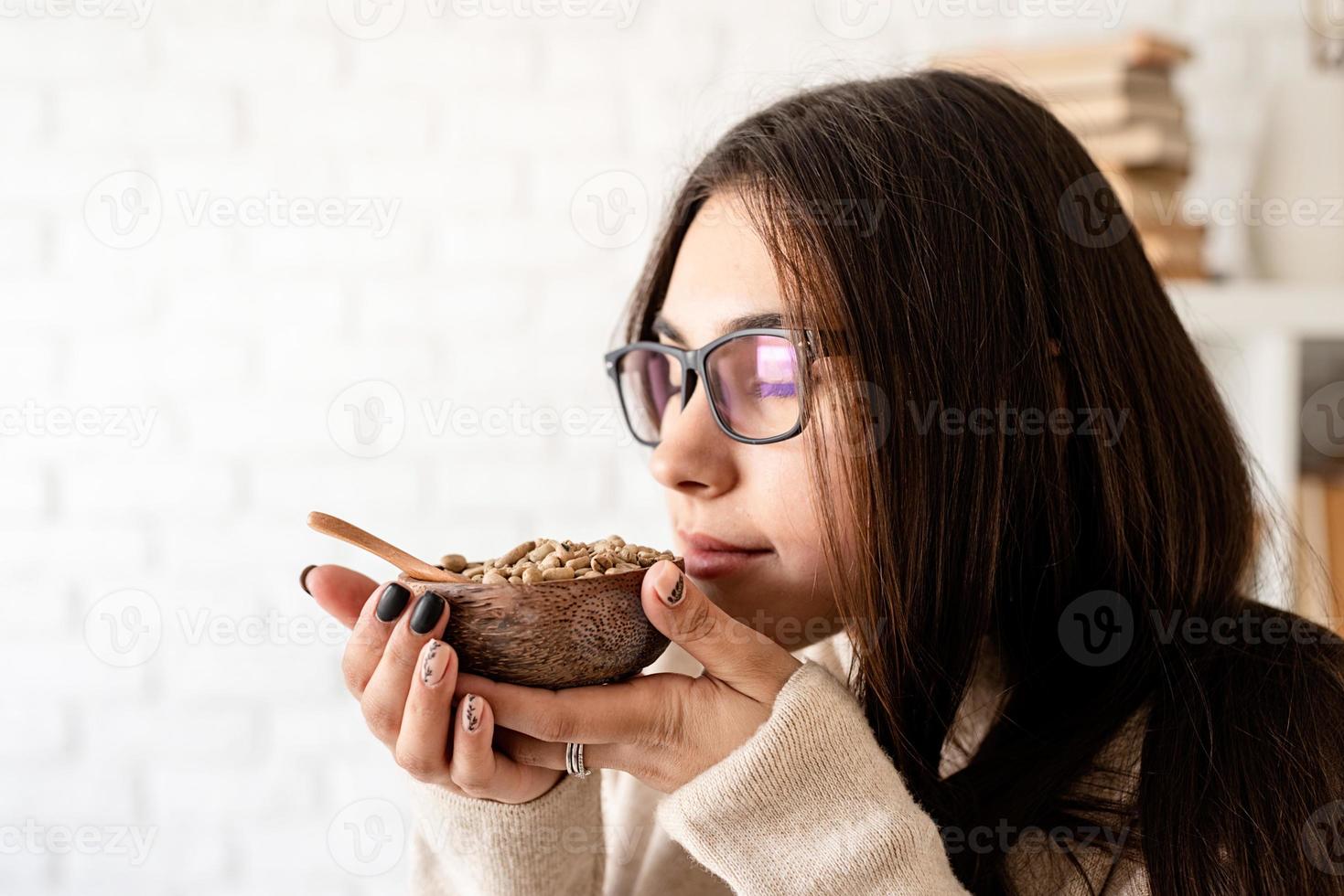 Frau, die Kaffee in der Kaffeekanne brüht und grüne Kaffeebohnen riecht foto