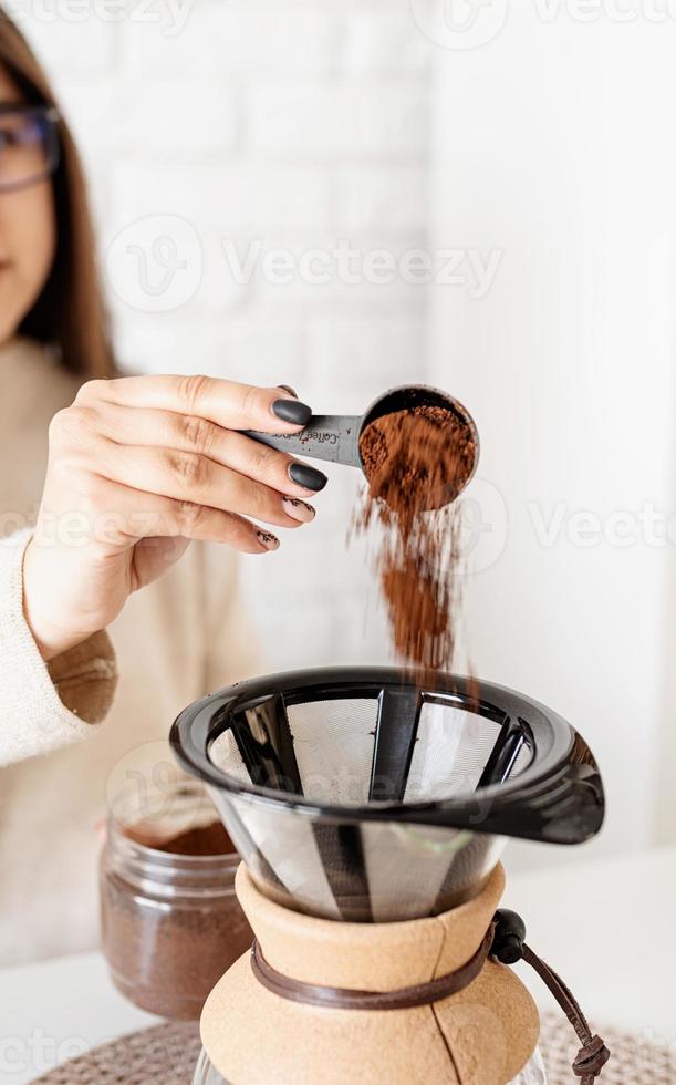 Frau, die Kaffee in der Kaffeekanne brüht foto