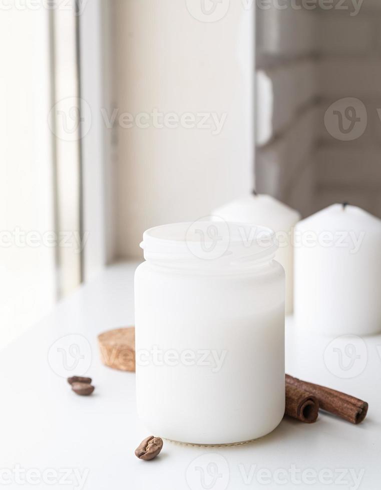 Kerze mit Zimtstangen und Kaffeebohnen auf weißem Hintergrund foto