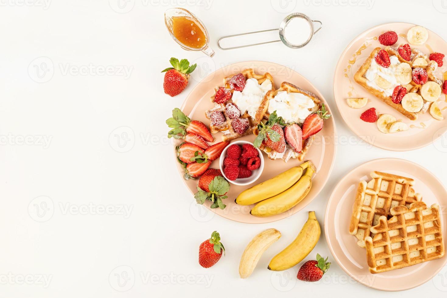 Waffeln mit Früchten und Beeren, Sahne und Honig in einem Teller foto