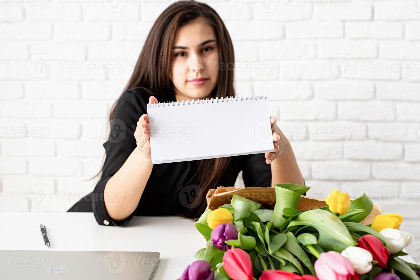 einen leeren Tischkalender halten, mit Blumen im Büro arbeiten foto