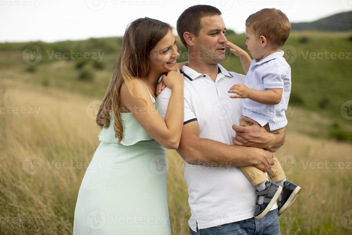 junge Familie mit süßem kleinen Jungen, der Spaß im Freien auf dem Feld hat foto