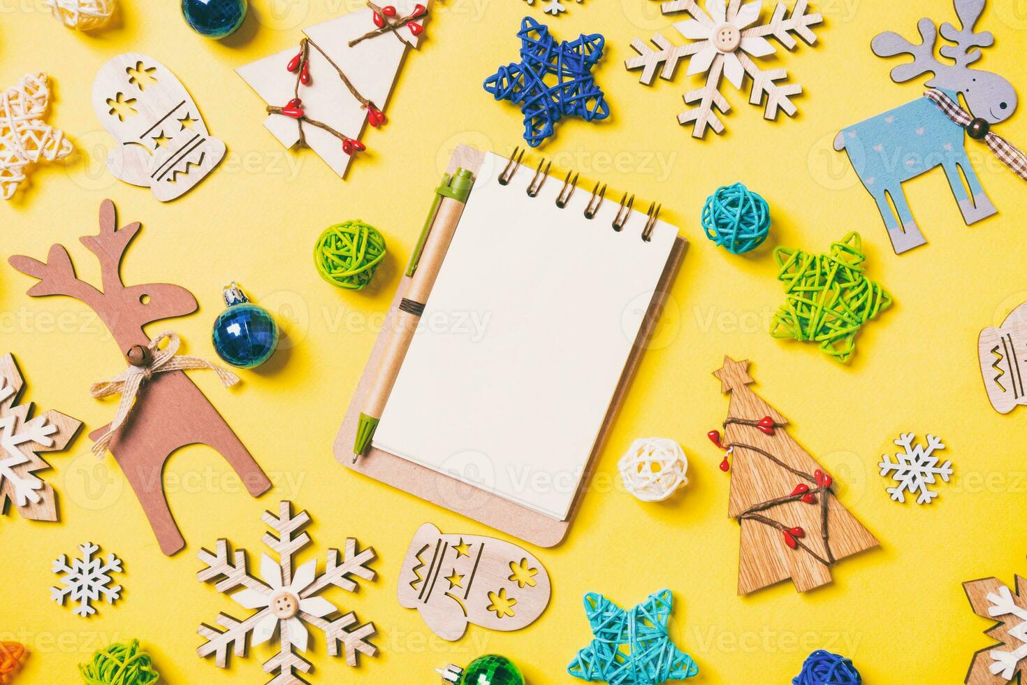 Draufsicht des Notebooks auf gelbem Hintergrund mit Spielzeug und Dekorationen des neuen Jahres. Weihnachtszeit-Konzept foto