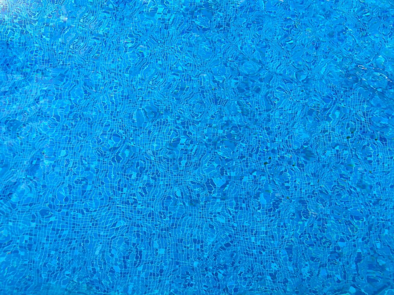 Oberfläche von Blau Schwimmen Schwimmbad Unterseite Ätzmittel Welligkeit und fließen mit Wellen Hintergrund. hell Blau zerrissen Wasser im Schwimmen Schwimmbad, Sommer- Hintergrund. Textur von Wasser Oberfläche. oben Sicht. foto