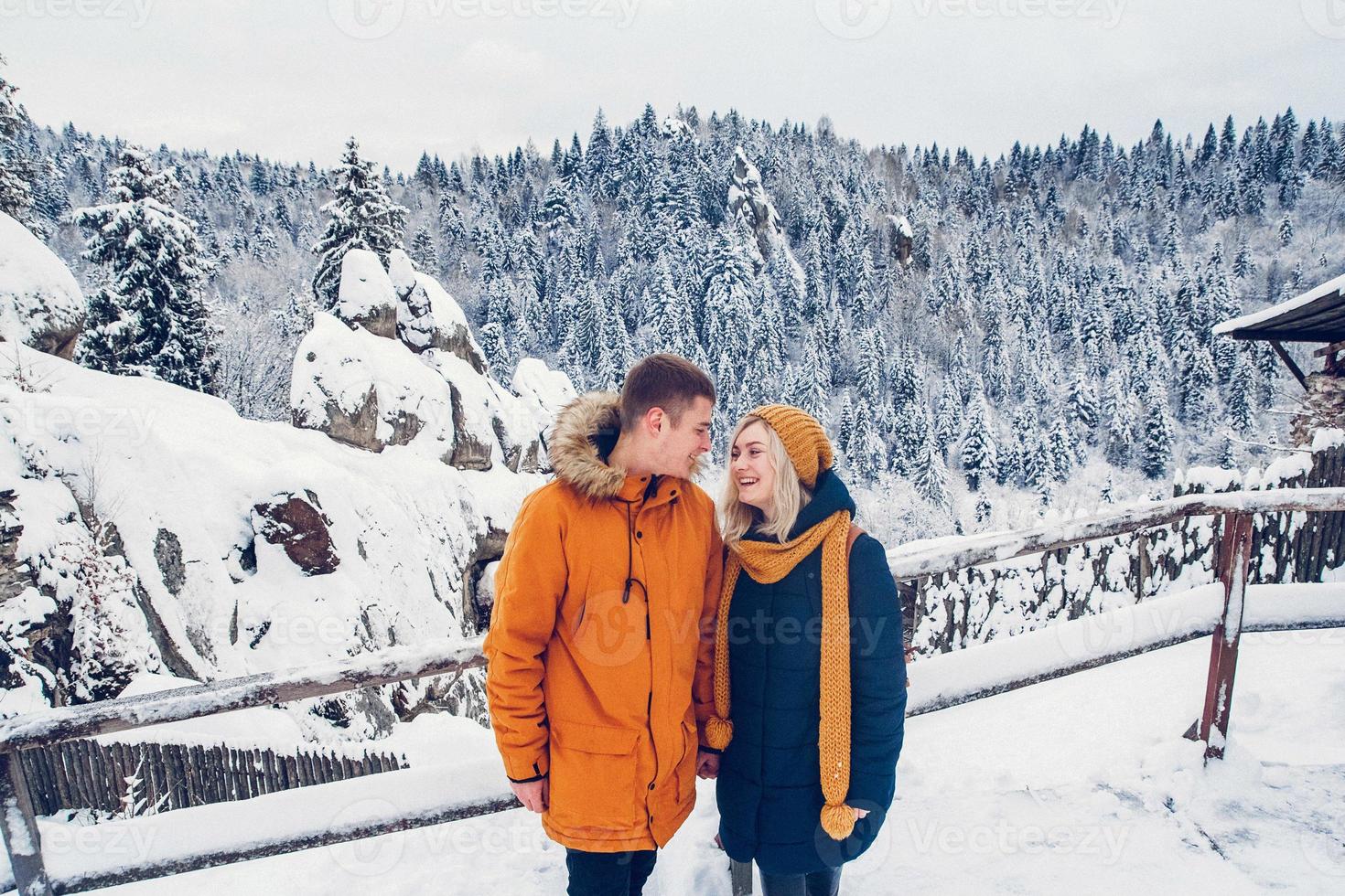 Paar kuschelt draußen in der Schneelandschaft in schweren Wintermänteln foto