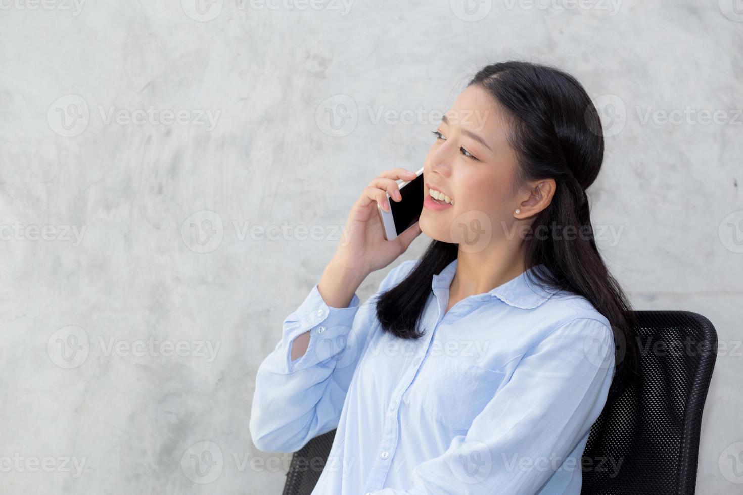 junge asiatische Frau, die Smartphone und Lächeln spricht. foto