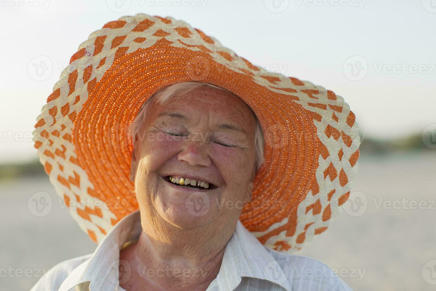 das Gesicht von ein alt Frau. Oma auf Urlaub. heiter alt Dame im ein Hut Lachen glücklich. Lächeln mit künstlich Zähne foto