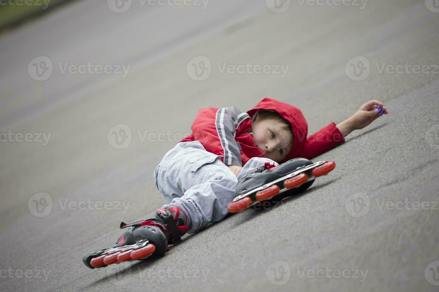 das Junge im Walze Rollschuhe Lügen auf das Pflaster.die Kind im Walze Rollschuhe fiel foto