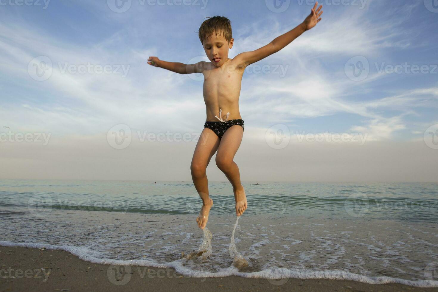 das Kind springt aus von das Wasser. das Junge springt auf das Ozean. Ferien beim das Strand foto