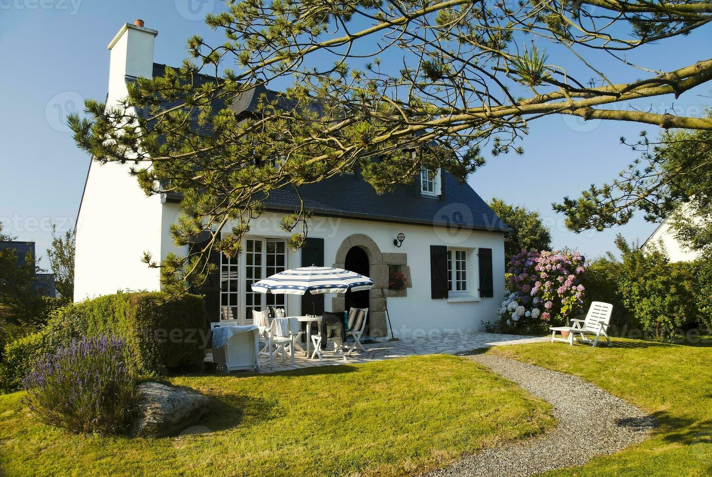 charmant Bretonisch Weiß Hütte mit Schiefer Dach im schön Garten foto