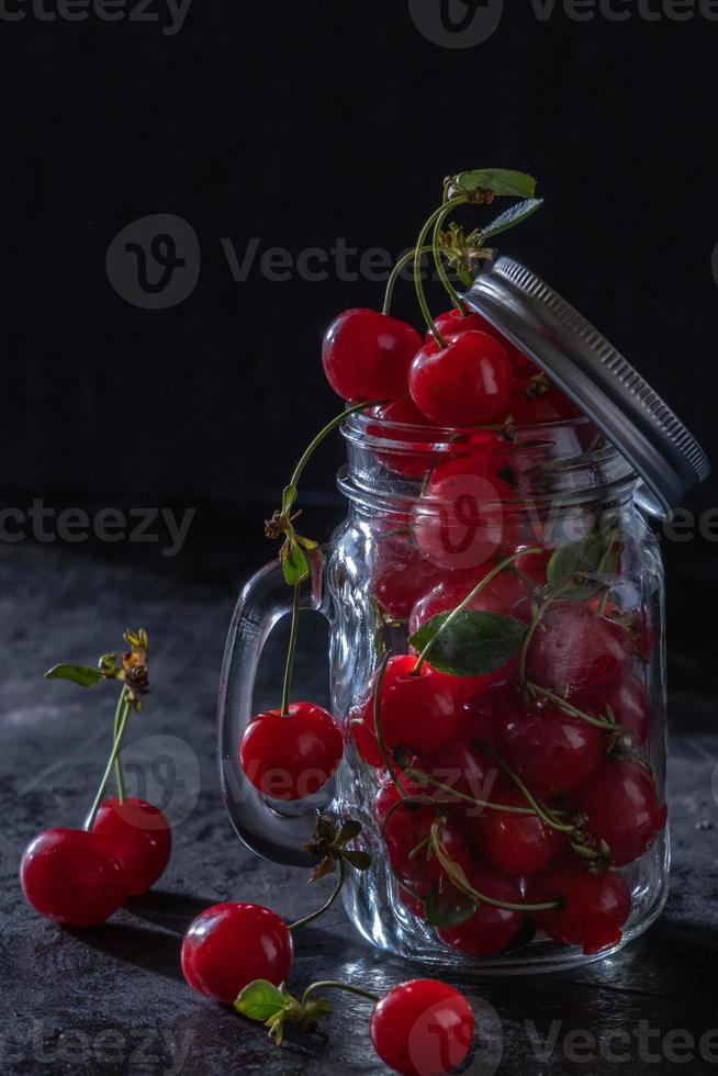 Süßkirsche in einem Glas auf schwarzem Hintergrund. saftige Früchte, zurückhaltend foto