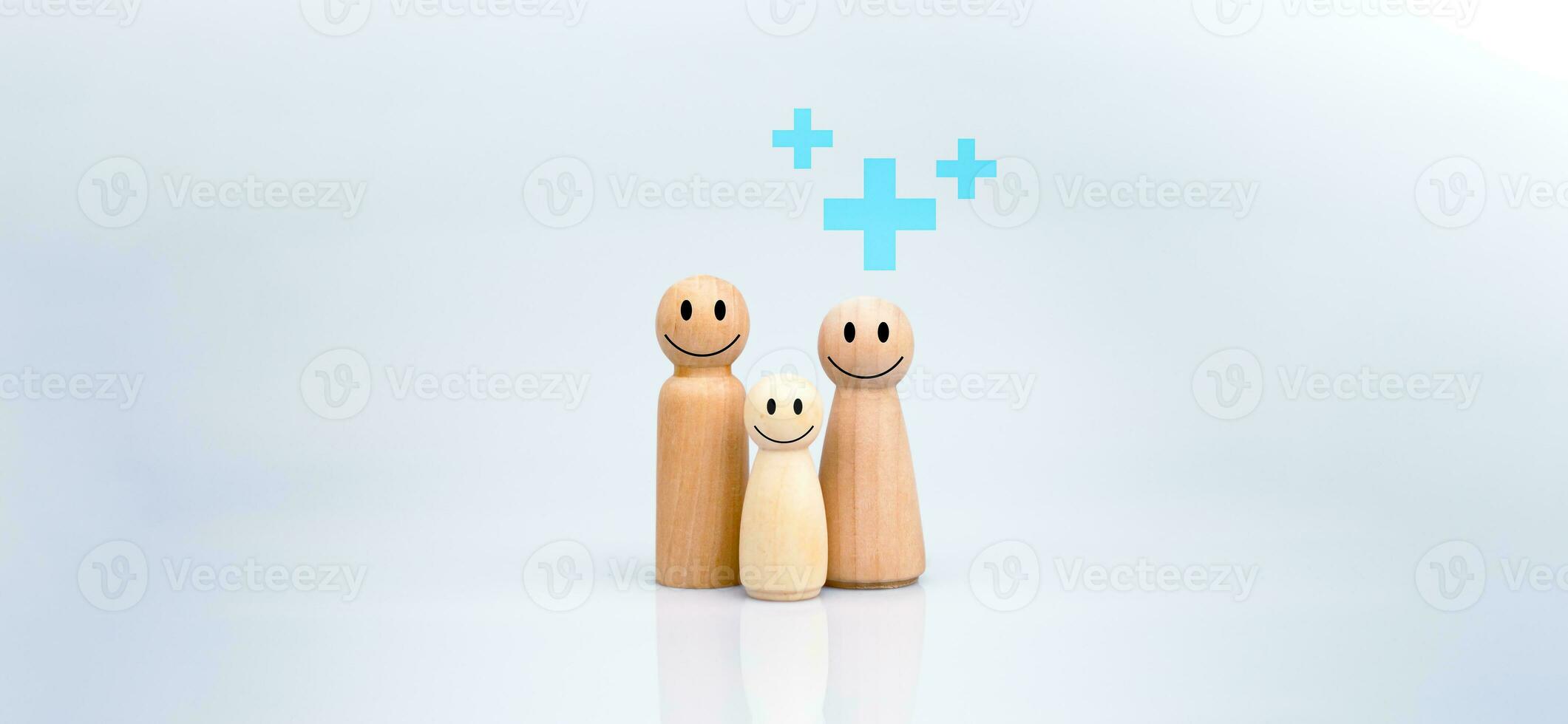 das Konzept von Gesundheit Versicherung und medizinisch Wohlfahrt. ein Familie von hölzern Puppen mit ein Plus Zeichen auf ein Weiß Hintergrund repräsentiert Schutz, Empfang Vorteile. Gesundheit Pflege Planung foto
