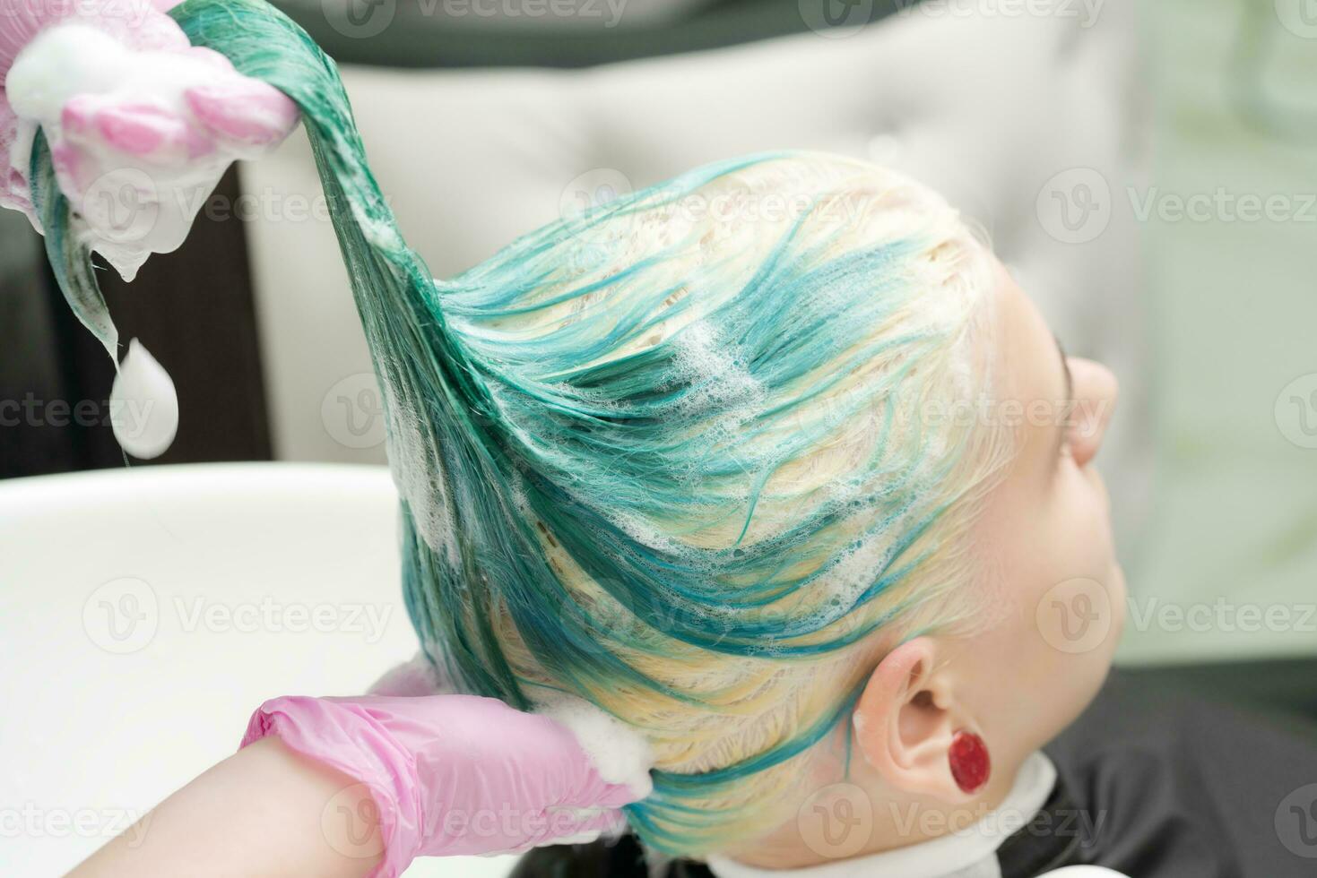 Waschen Grün Haar Farbe von jung Frau mit Shampoo im Haar Salon foto