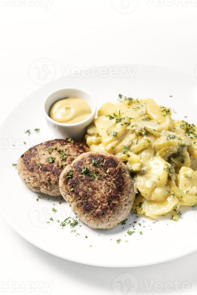 Frikadellen Frikadellen mit cremigen Zwiebeln Bratkartoffeln und Senfsauce auf weißem Teller foto