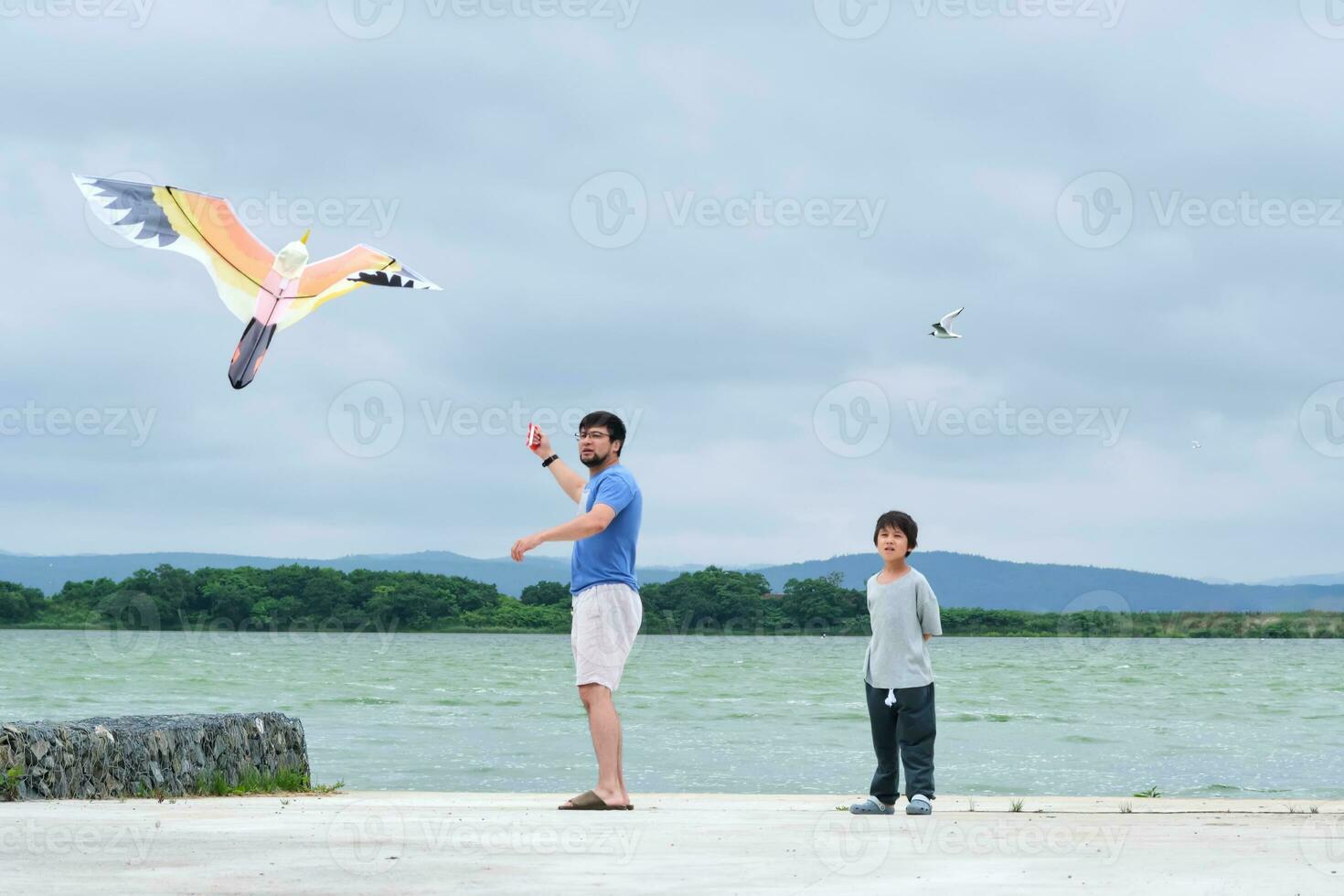 ein Junge und seine Papa fliegen ein Drachen. foto