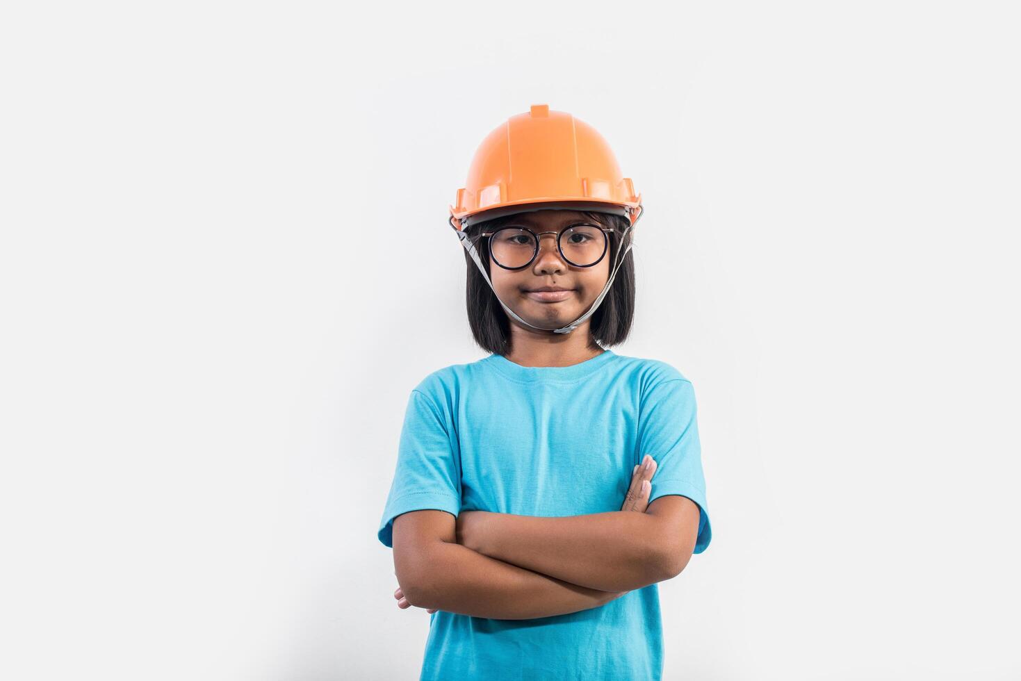 kleines Mädchen mit orangefarbenem Helm in Studioaufnahme. foto