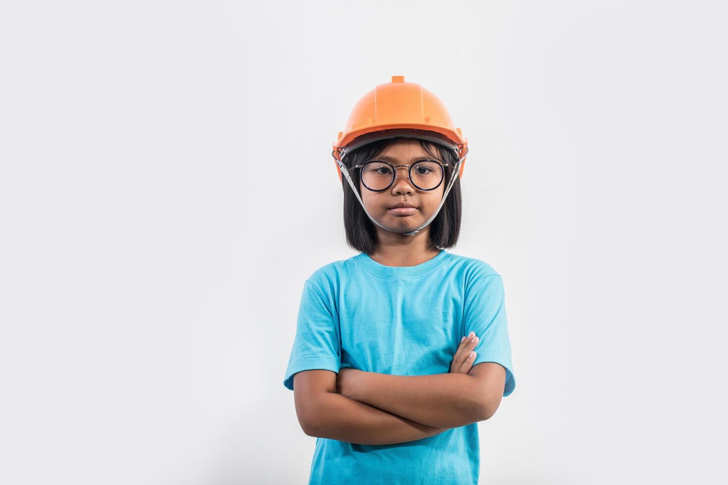 kleines Mädchen mit orangefarbenem Helm in Studioaufnahme. foto