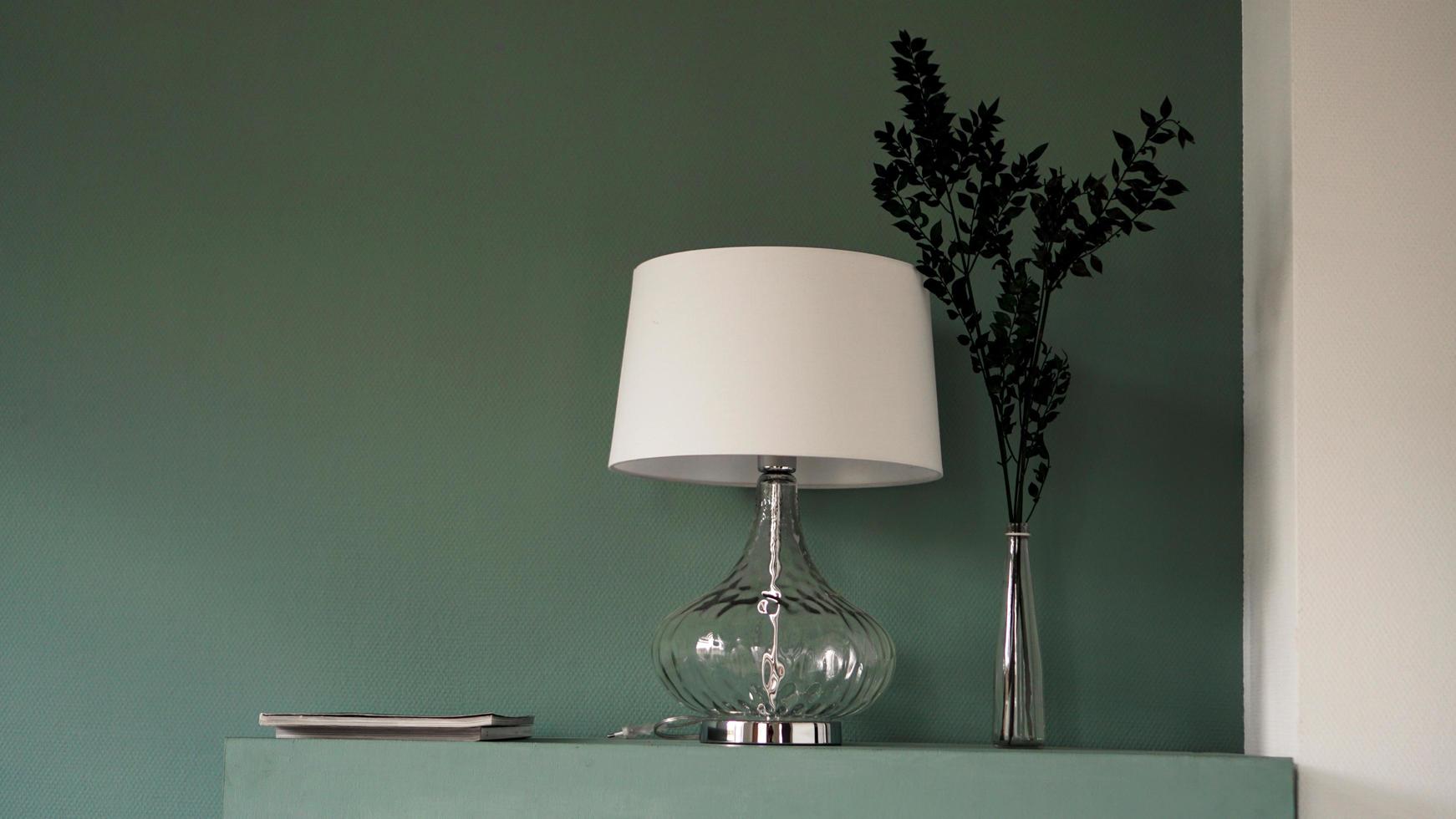 weiße Stehlampe und Vase auf grünem Hintergrund foto