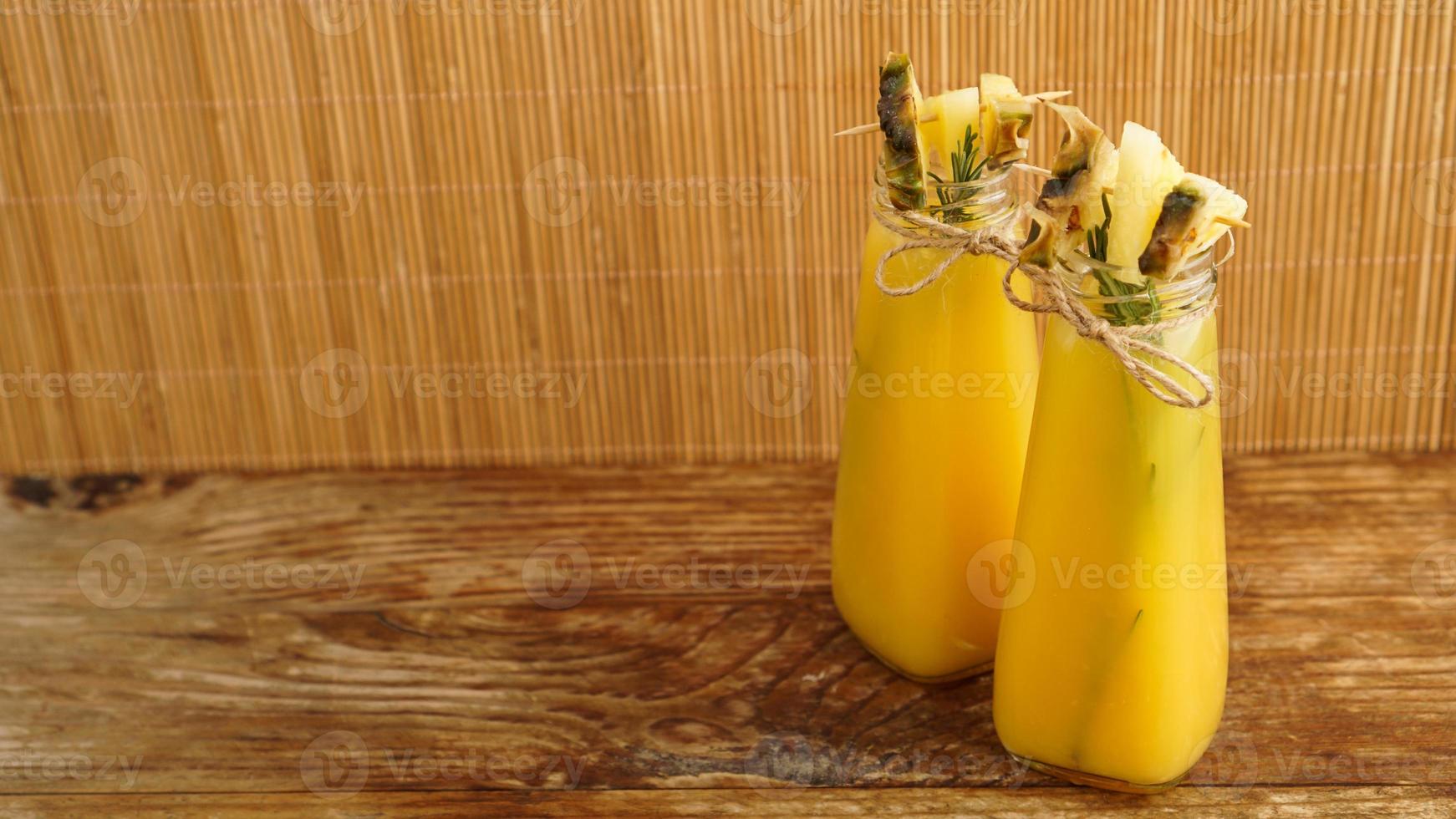 Ananassaft in einer kleinen Flasche. Ananasscheiben dekorieren das Getränk foto