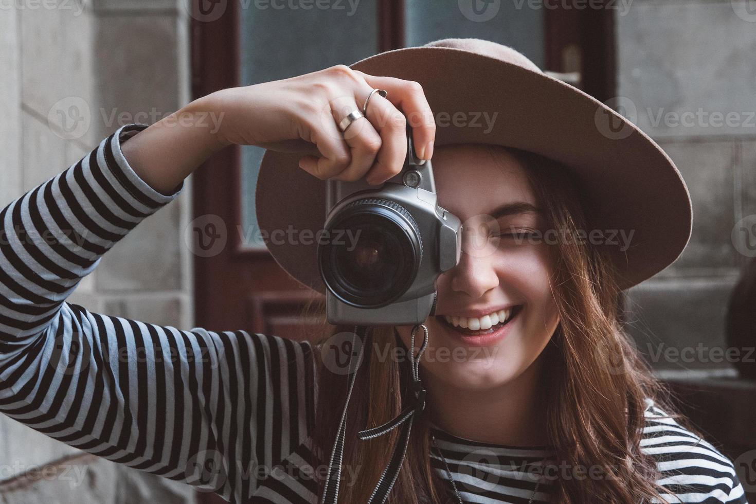 schöne Frau mit Hut macht ein Foto mit altmodischer Kamera