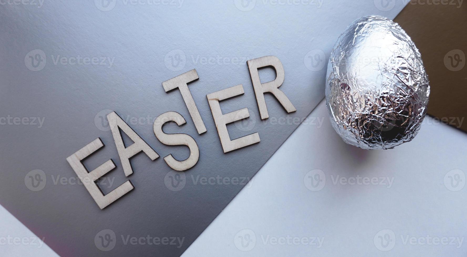 Ei in Folie auf silbernem Hintergrund. Ostern Konzept. mit Text Ostern foto