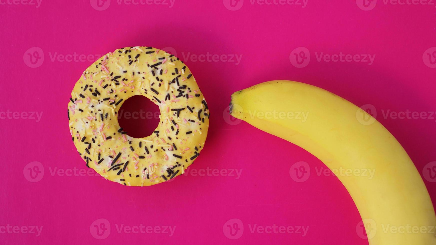 süßer Donut und Banane auf rosafarbenem Hintergrund. erotisches Konzept foto