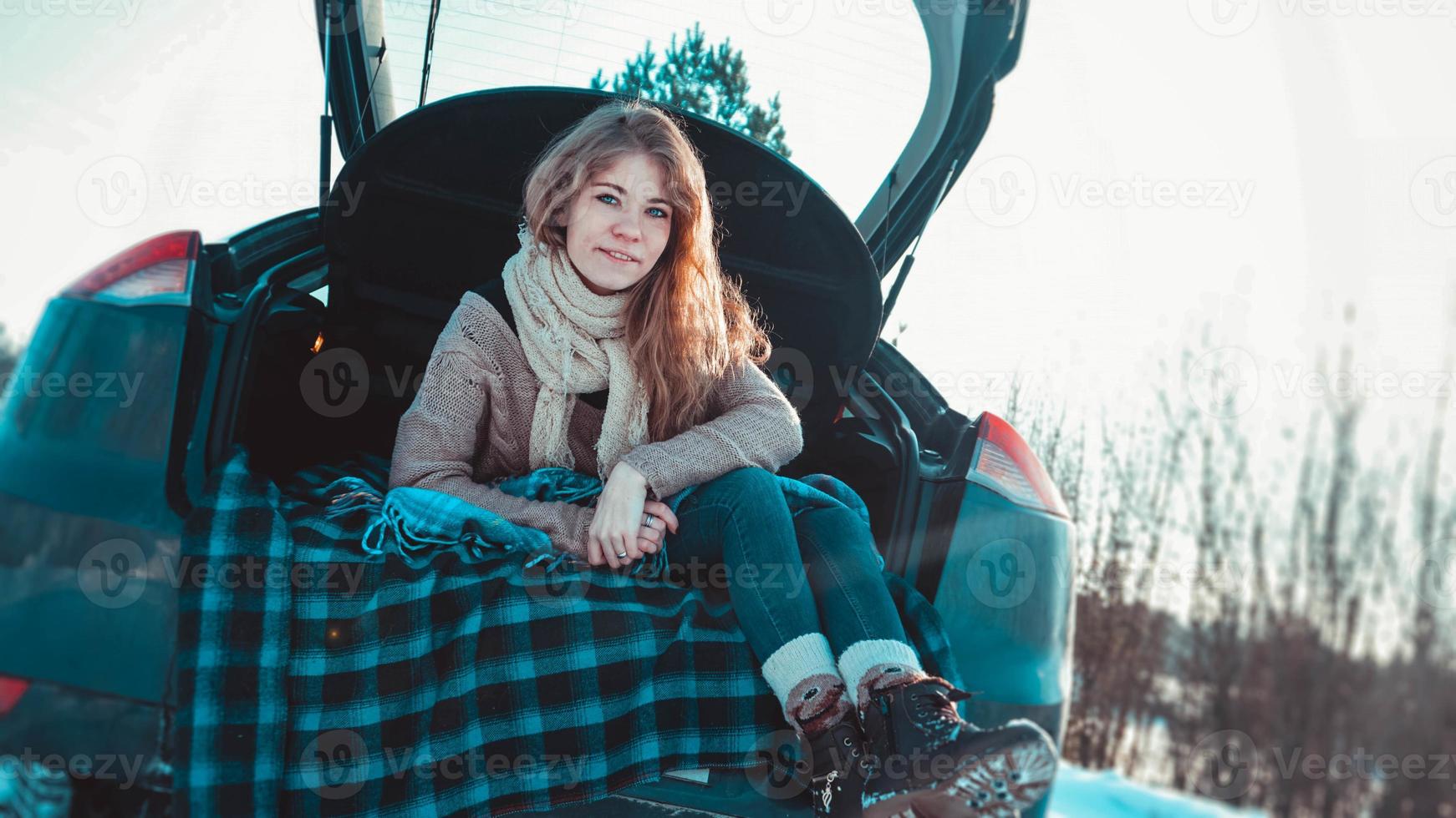 glückliches Mädchen, das auf LKW des Autos im Winterwald sitzt foto