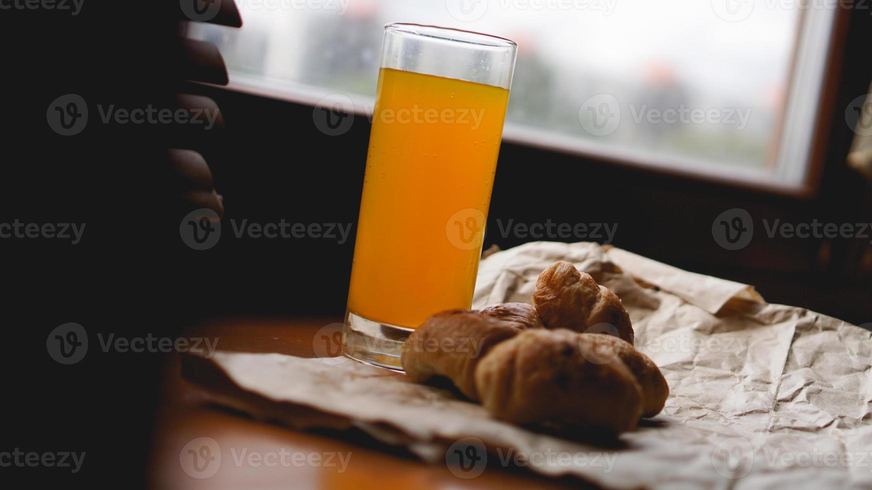 frisch gebackene Croissants mit Orangensaft auf Kraftpapier foto