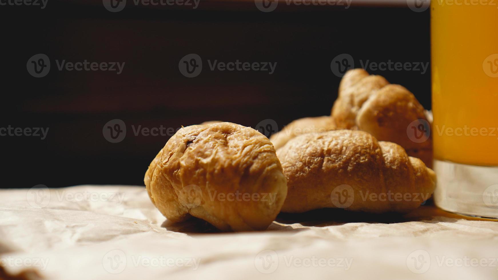 frisch gebackene Croissants mit Orangensaft auf Kraftpapier foto