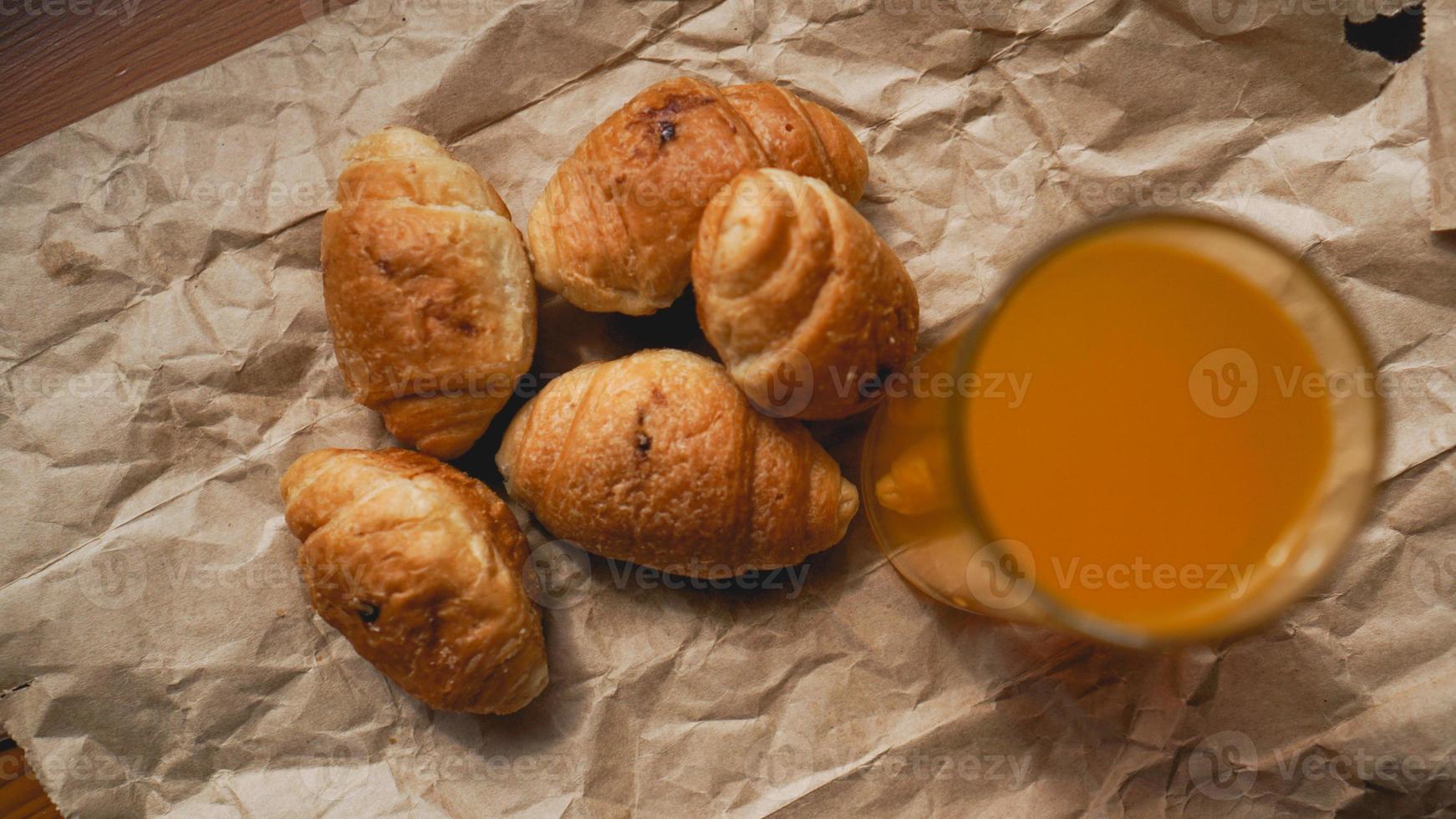 frisch gebackene Croissants mit Orangensaft auf Kraftpapier foto