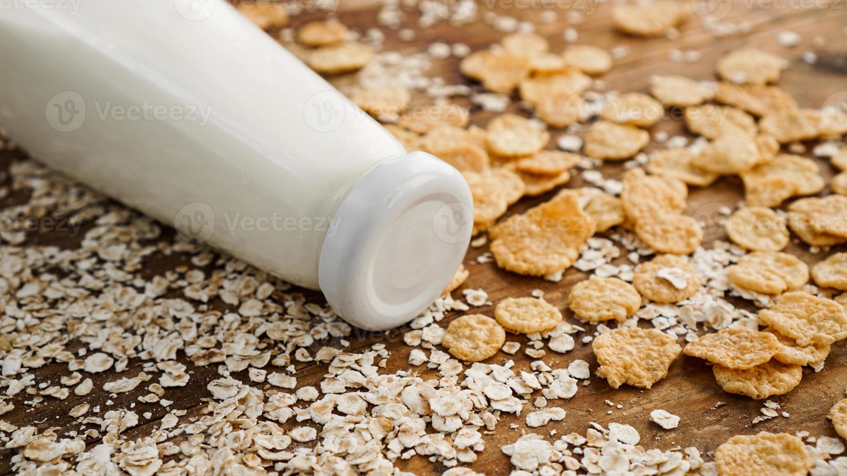 frische Milchflasche auf Holzuntergrund mit Hafer und Getreide foto