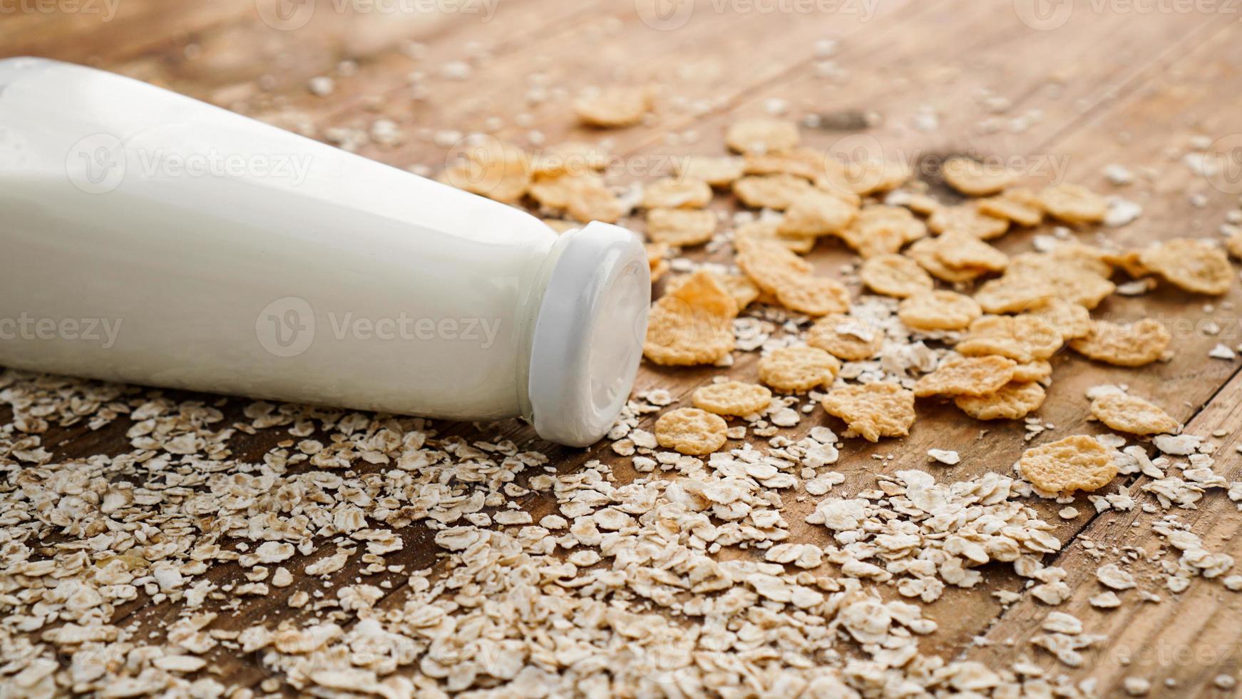 frische Milchflasche auf Holzuntergrund mit Hafer und Getreide foto