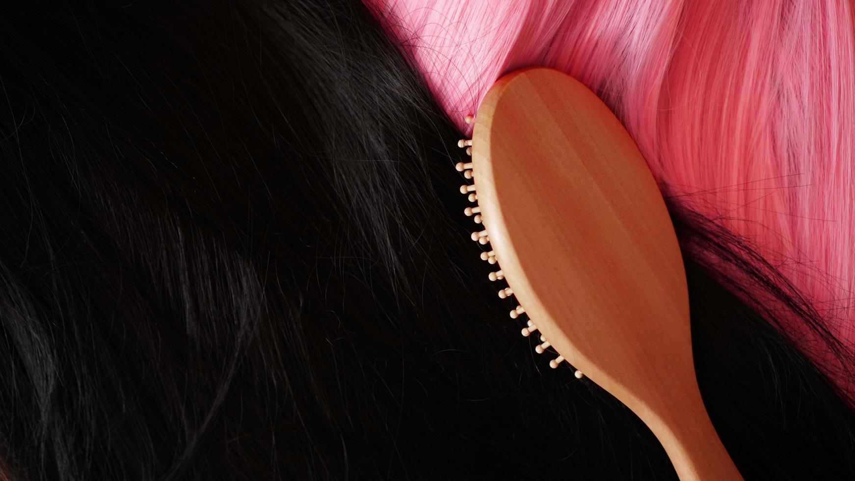 rosa und schwarze Perücke mit langen Haaren und Kämmen ein Holzkamm foto