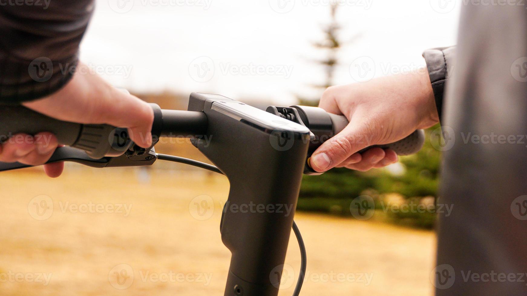 Nahaufnahme der männlichen Hand, die die Geschwindigkeitstaste auf dem Elektroroller drückt foto