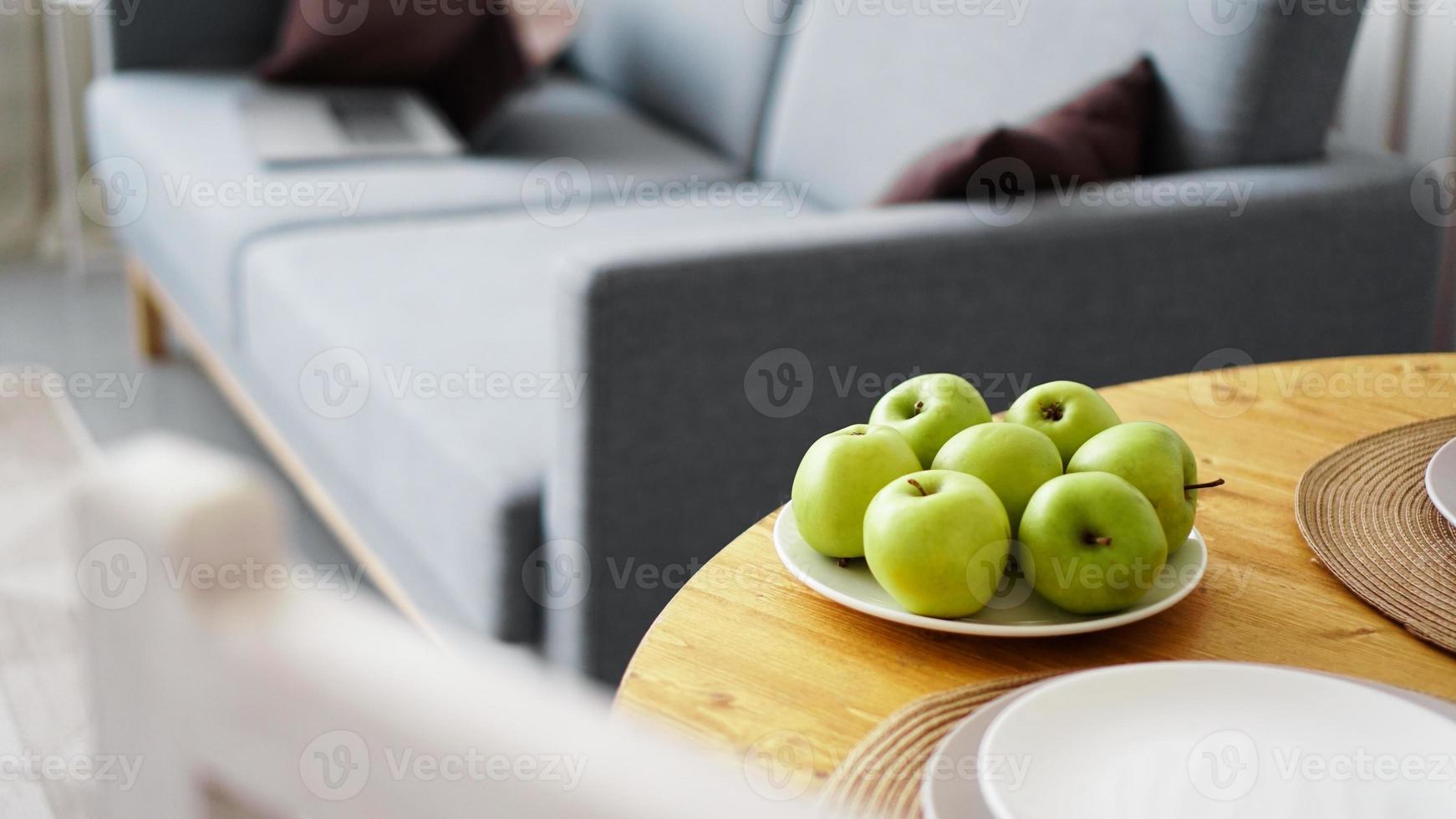 grüne Äpfel auf einem weißen Teller auf einem Holztisch foto