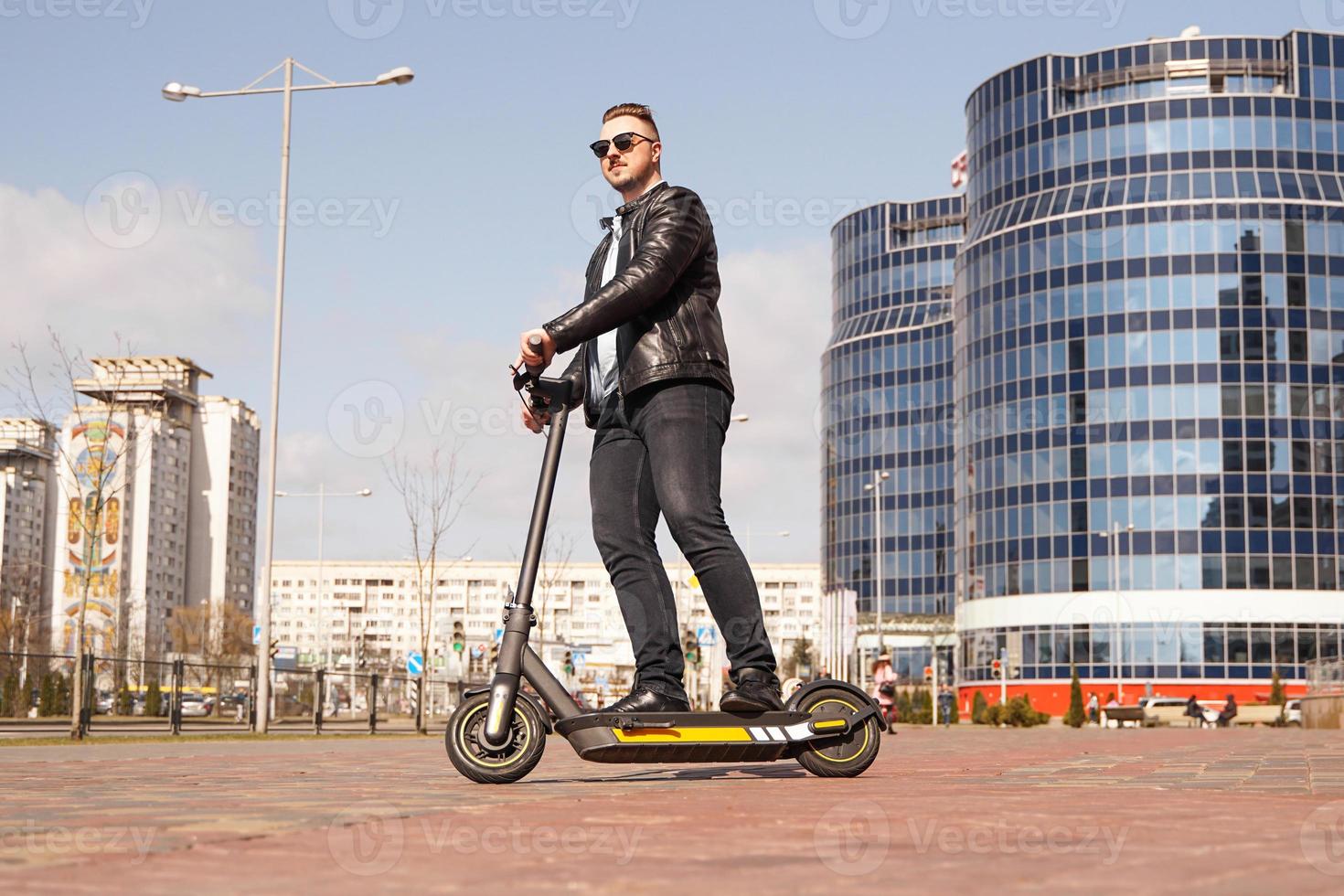 moderner Mann, der Elektroroller in der Stadt fährt foto