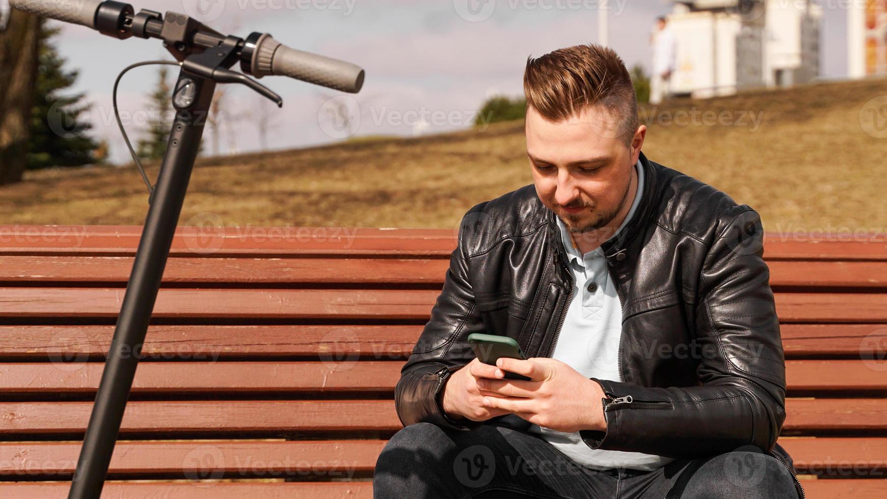 junger Mann sitzt an einem Frühlingstag auf einer Bank foto