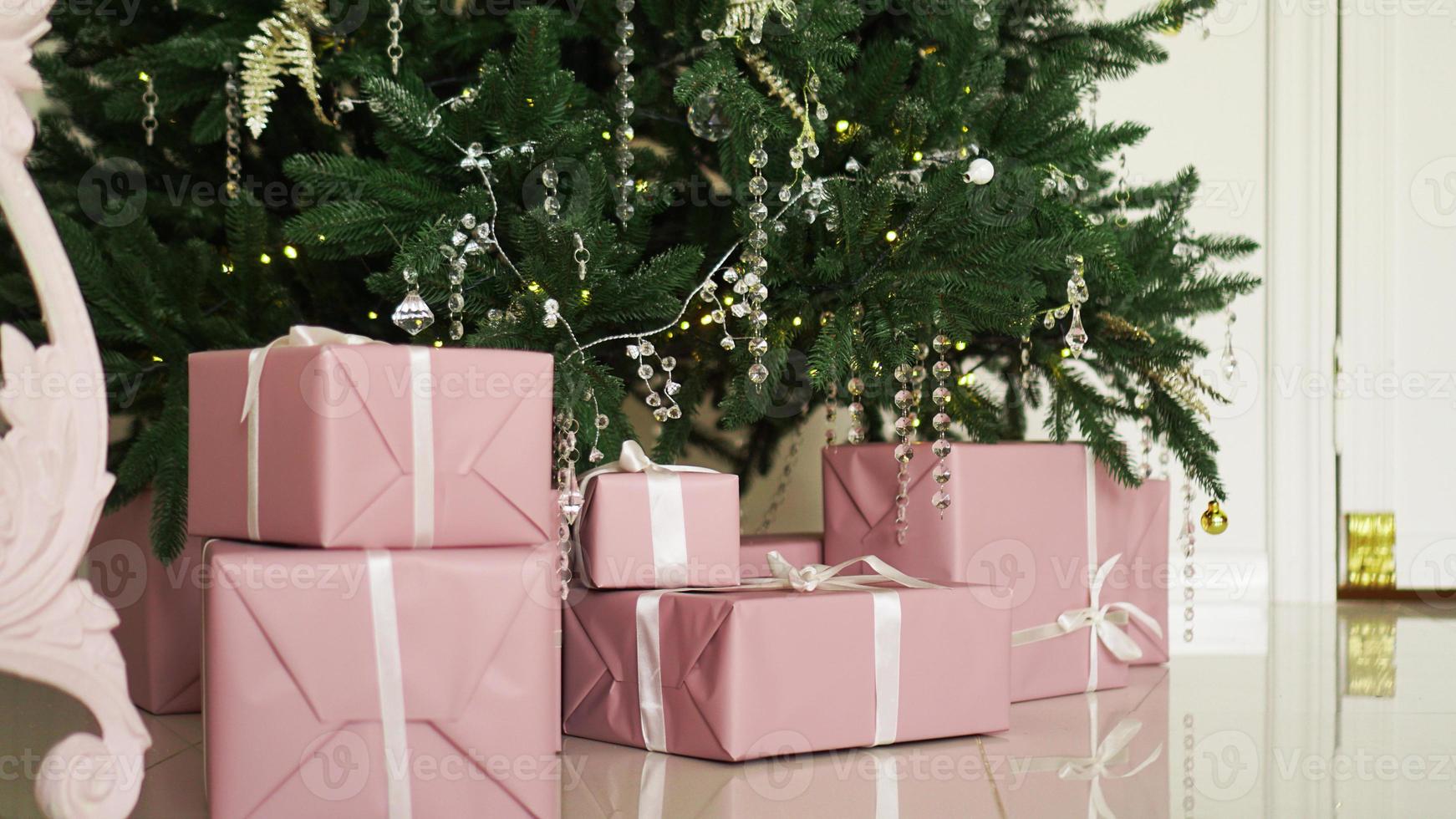 rosa Geschenkkartons mit Bändern unter dem Weihnachtsbaum foto