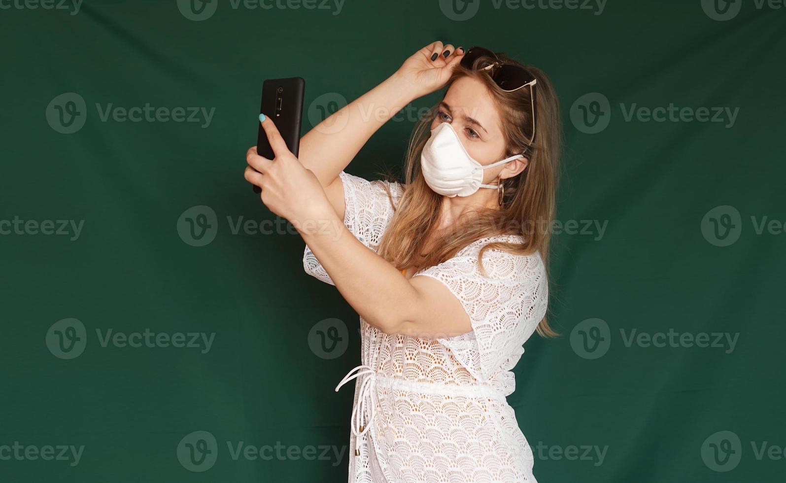 schönes Mädchen mit medizinischer Maske im Gesicht, das Selfie macht foto