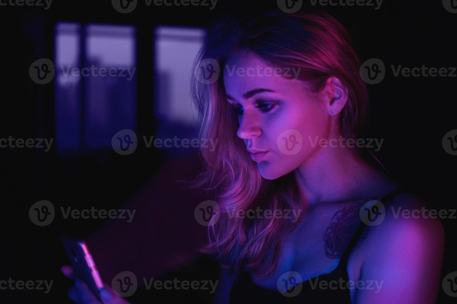 Mädchen mit Handy nachts mit Neonlicht foto