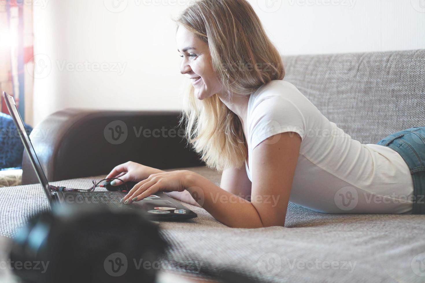 junge Frau entspannt sich mit einem Laptop in ihrem Wohnzimmer foto