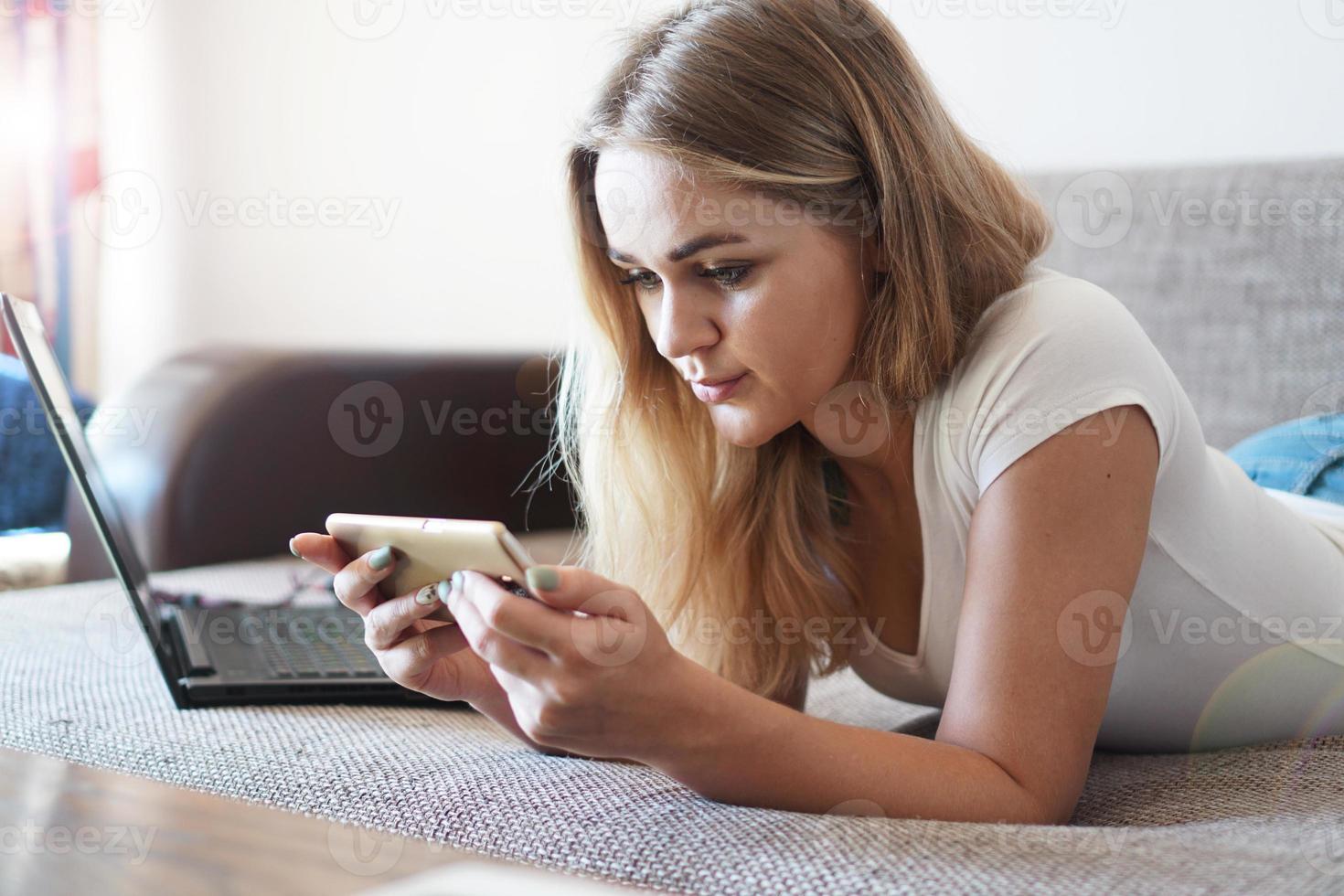 Attraktive junge Frau, die sich zu Hause auf einem Sofa entspannt foto