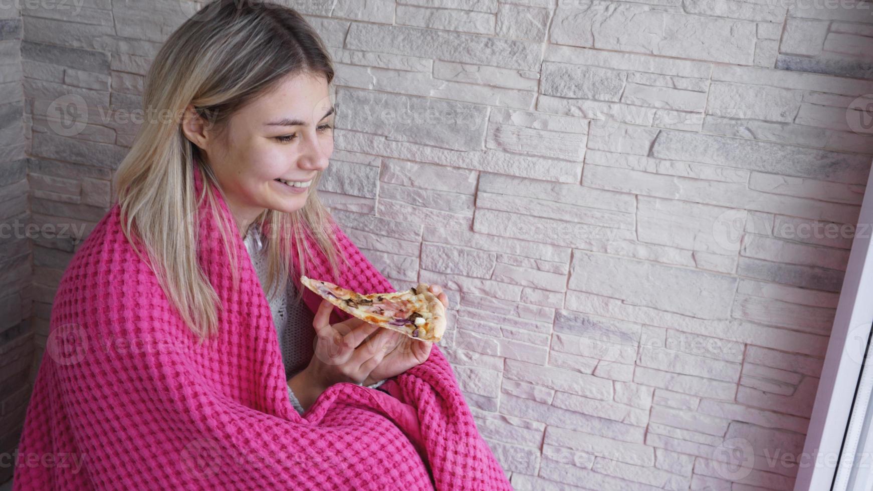 Schöne Frau mit rosa Plaid hält ein Stück Pizza foto