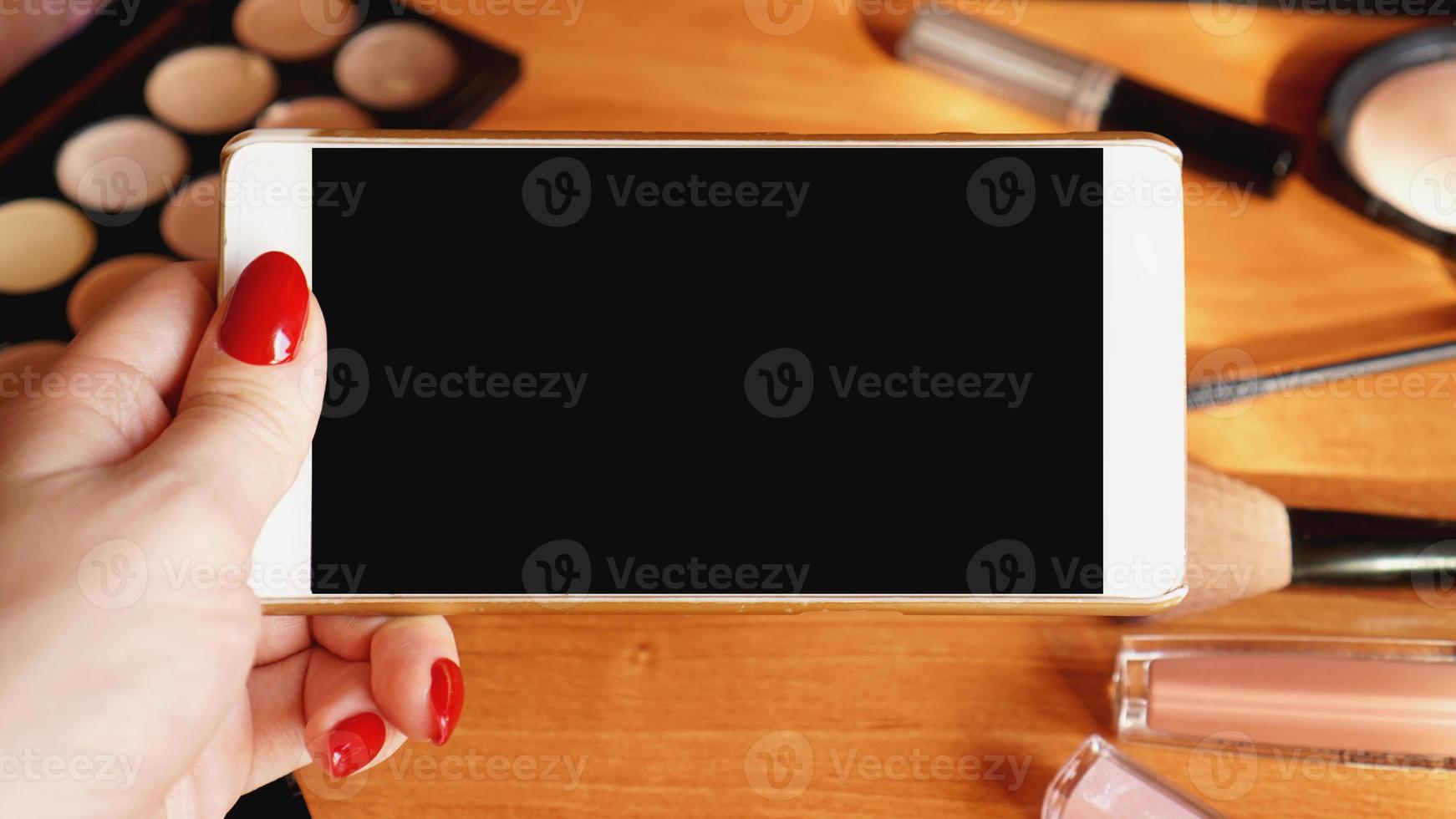 Smartphone mit leerem Bildschirm und Kosmetik auf Holzhintergrund foto