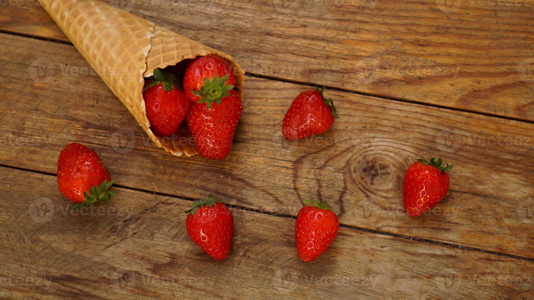 Eistüte mit Erdbeeren auf Holzuntergrund foto