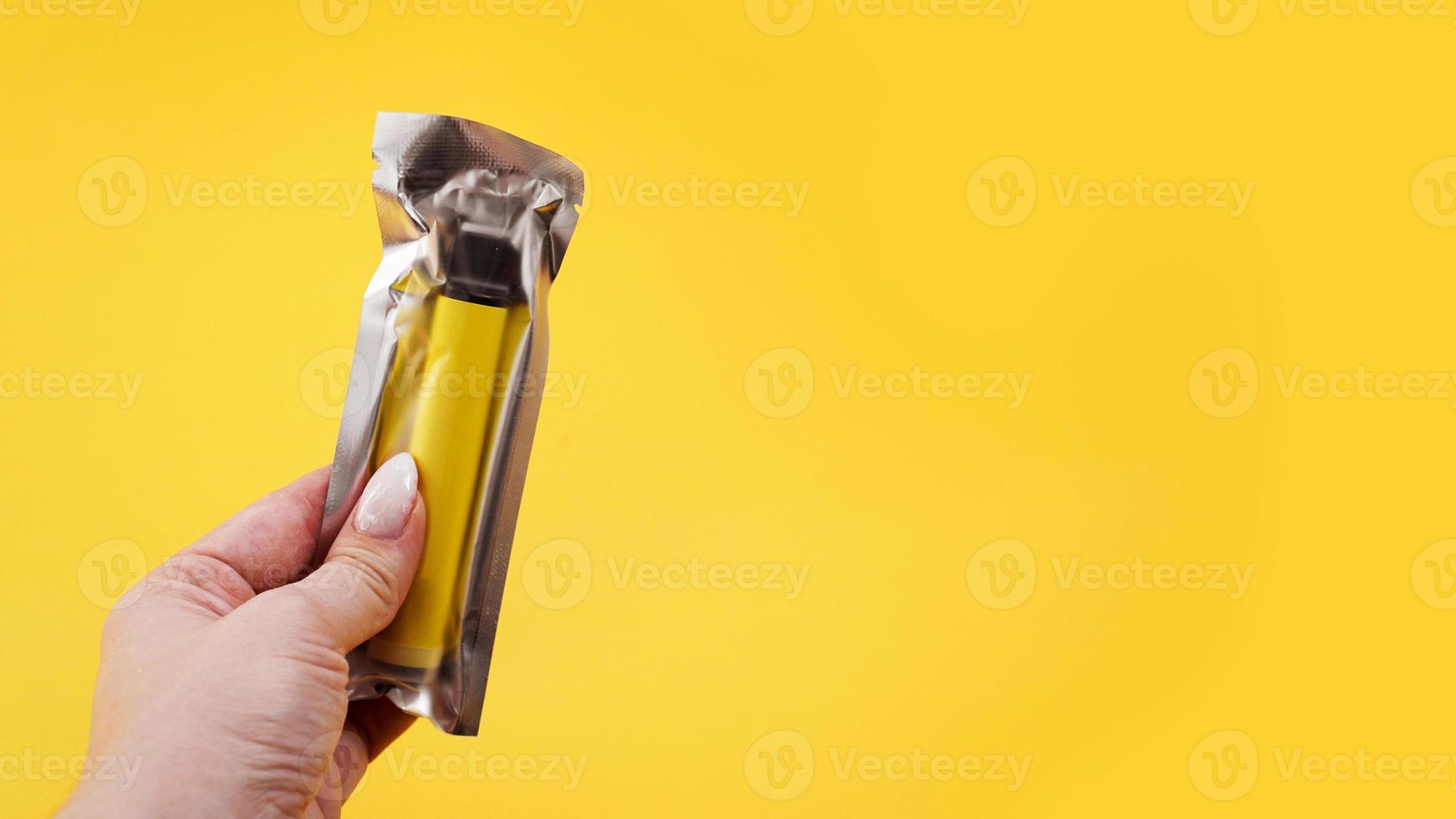 gelbe elektronische Einwegzigarette in der Verpackung in weiblicher Hand foto