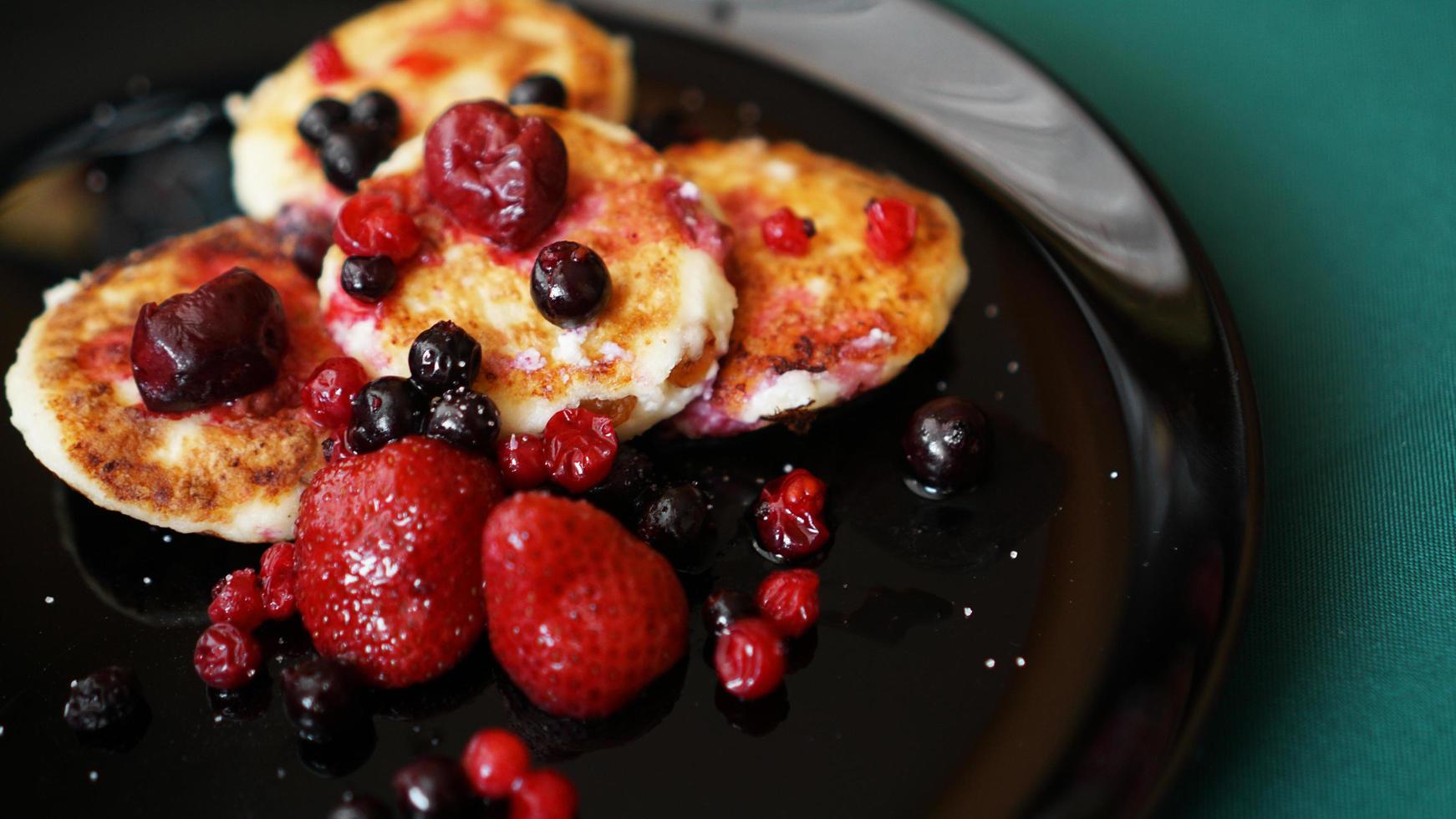 Käsepfannkuchen mit Beeren auf einem schwarzen Teller. foto