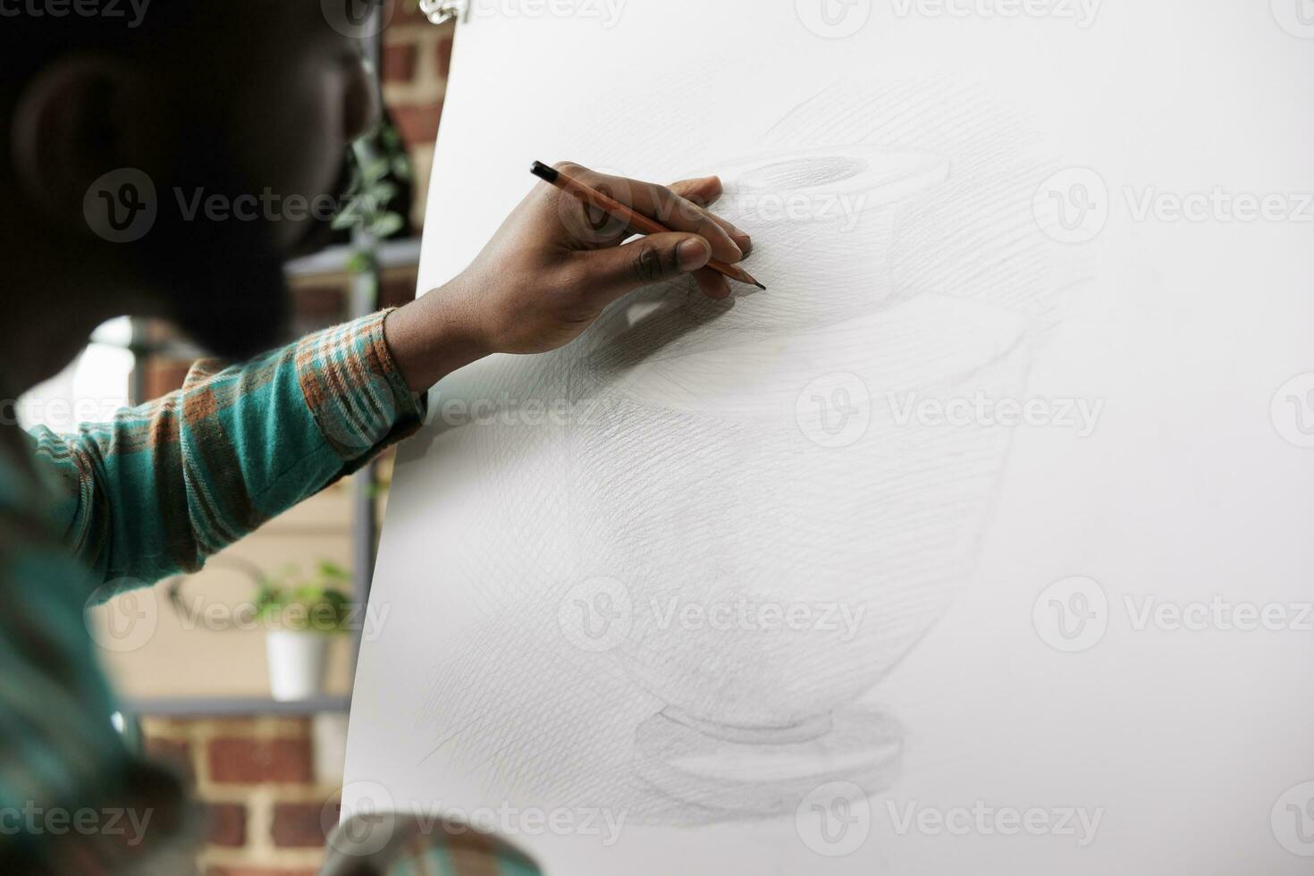 Schüler Kerl Zeichnung mit Bleistift auf Leinwand. afrikanisch amerikanisch Mann Künstler bleiben konzentriert während Erstellen Kunst im Studio oder Werkstatt, Sitzung beim Staffelei Skizzierung Basic Vase mit Bleistift foto