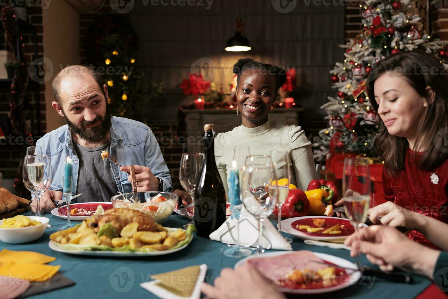 afrikanisch amerikanisch Frau beim Weihnachten Abendessen feiern Winter Urlaub mit Menschen Versammlung beim Tabelle und Essen traditionell hausgemacht Mahlzeit. Gruppe von heiter Personen genießen Weihnachten Veranstaltung beim heim. foto